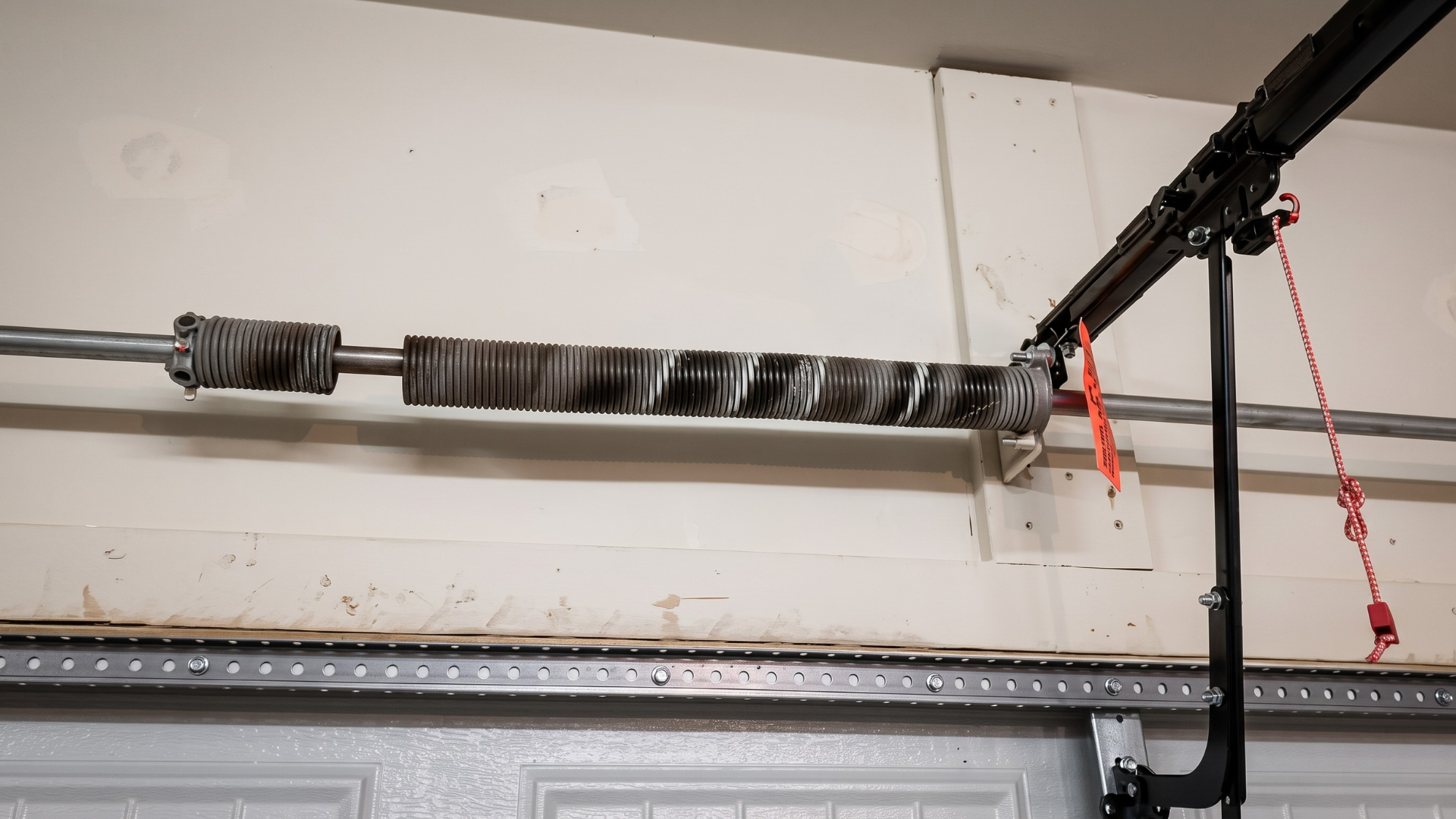 Garage door torsion spring and track mechanism mounted near the ceiling.