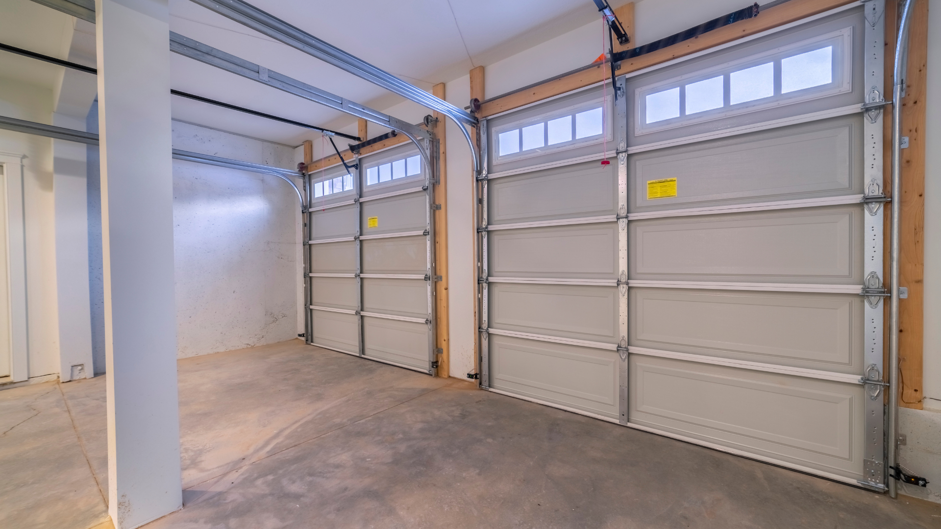 Empty industrial garage with white overhead doors and concrete floor