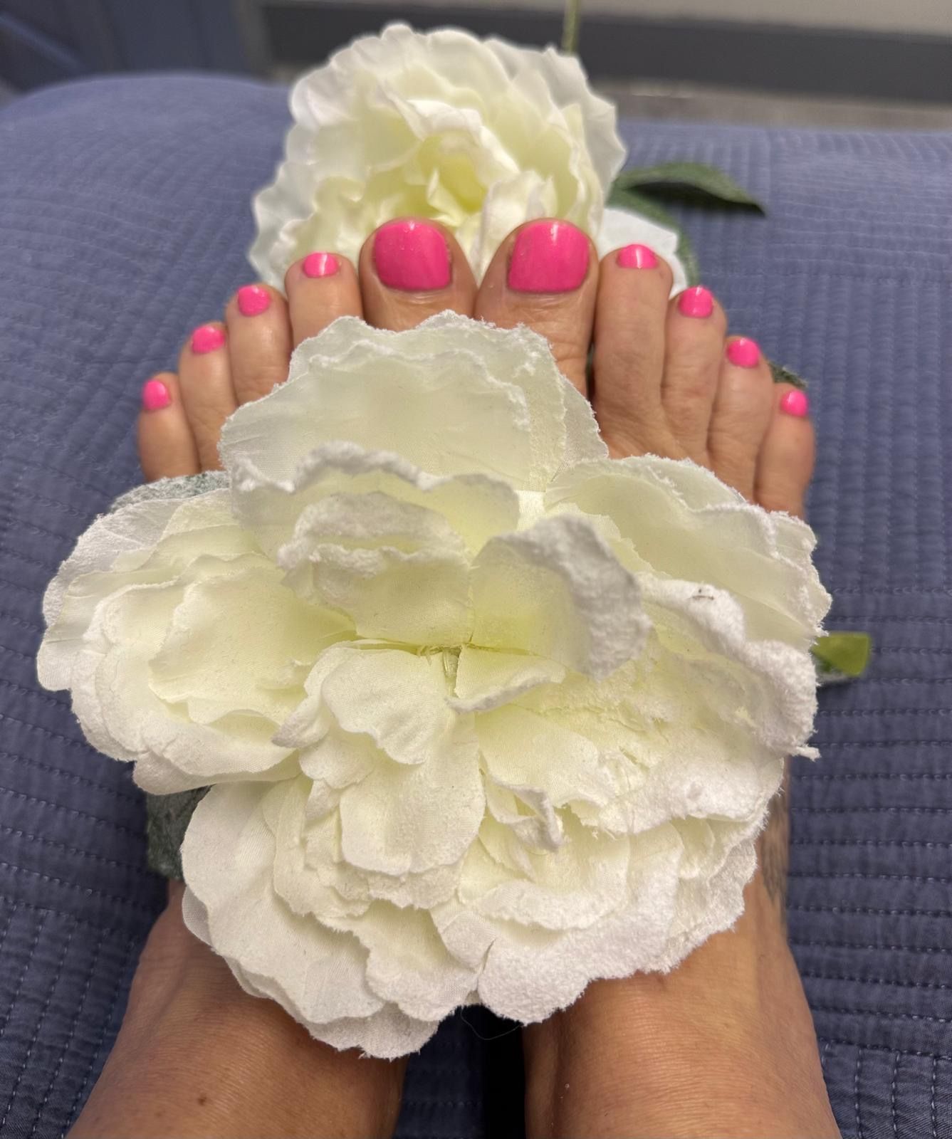 Bright pink pedicure with white flowers at The Pamper Lounge