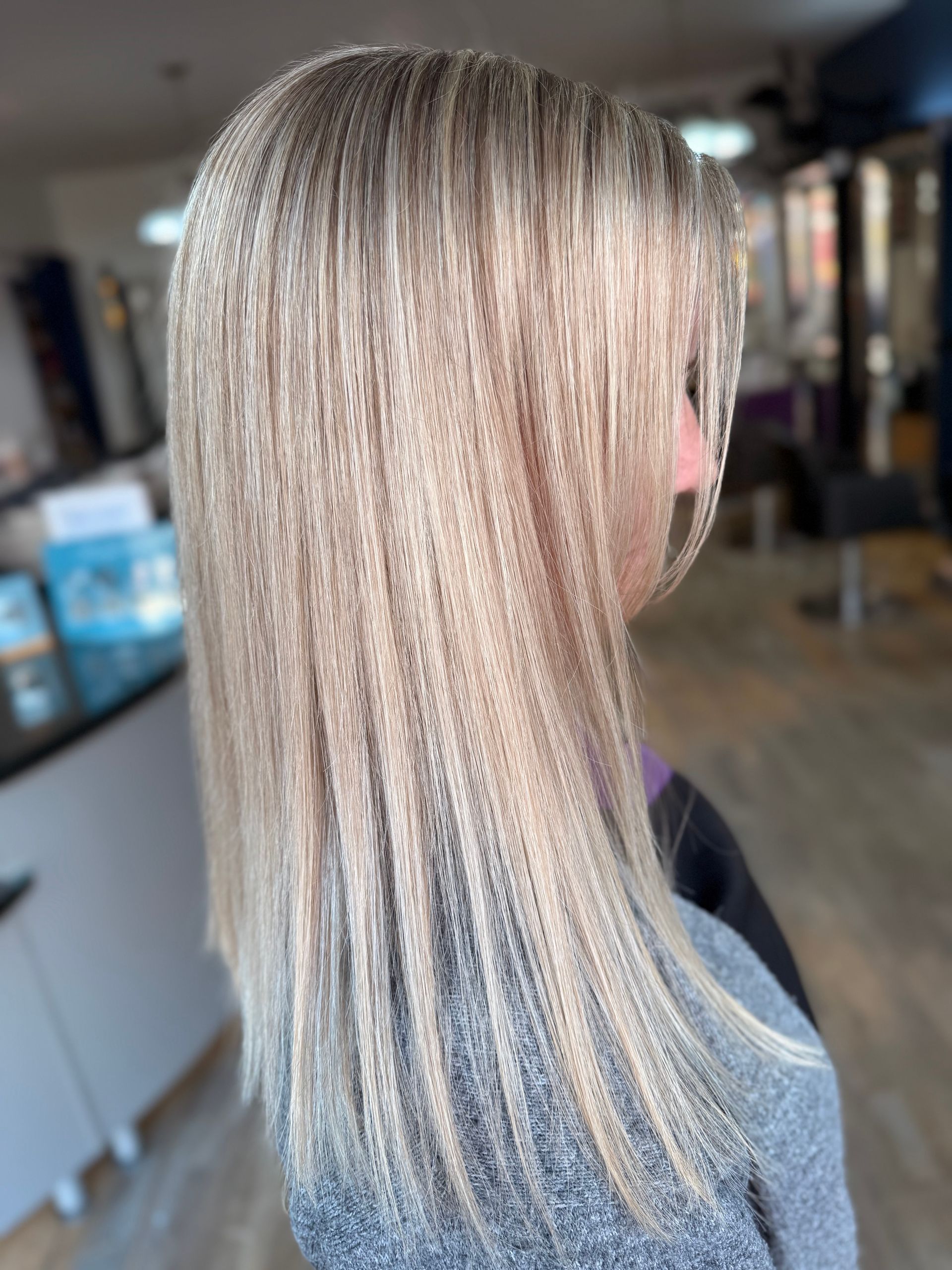 Straight blonde hair with subtle highlights shown from the back in a salon setting
