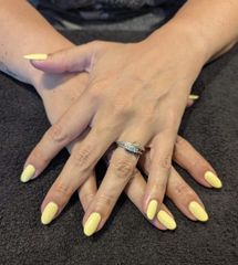 Hands crossed with long yellow nails and a silver ring on a dark textured background