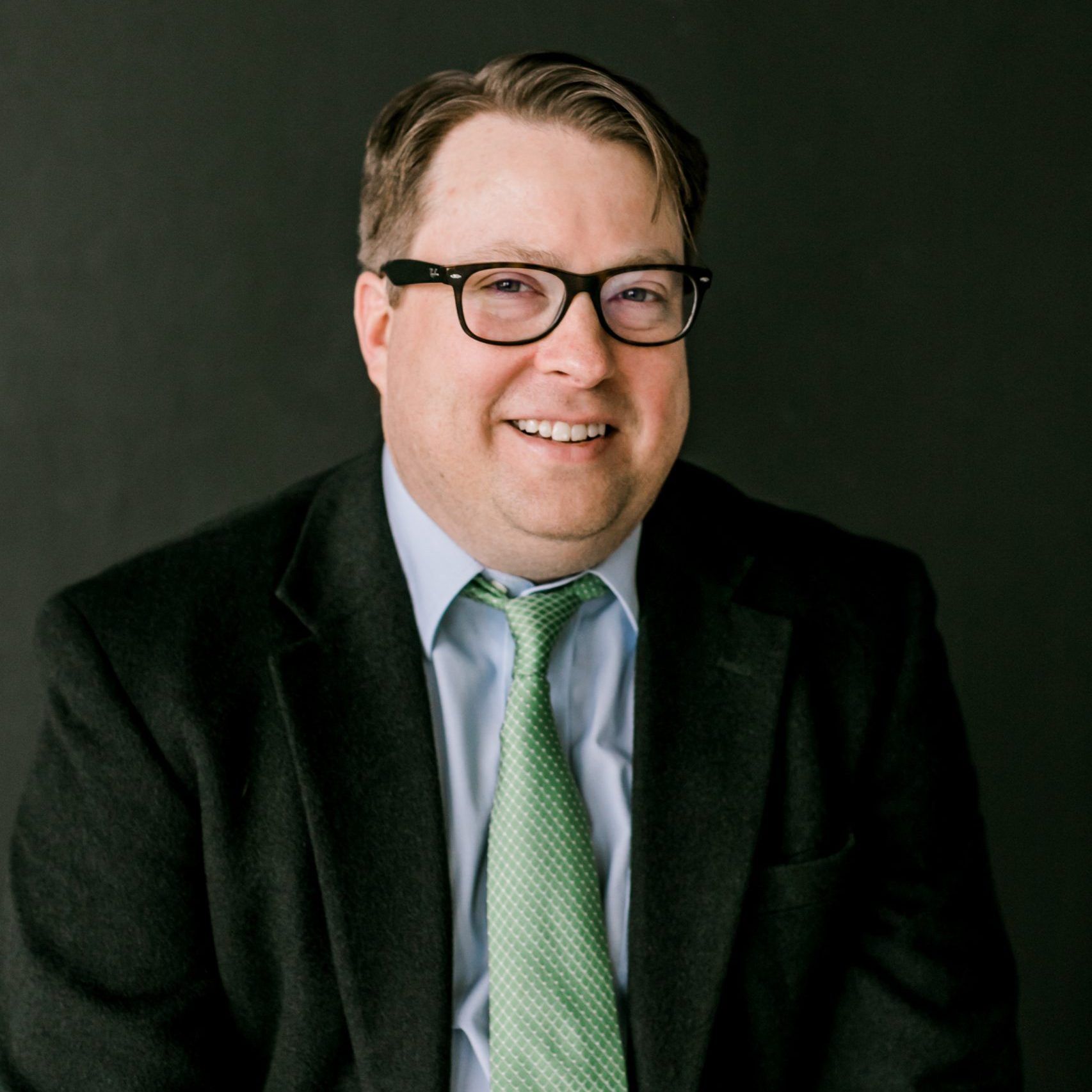 A man with a beard is wearing a blue suit and a bow tie.