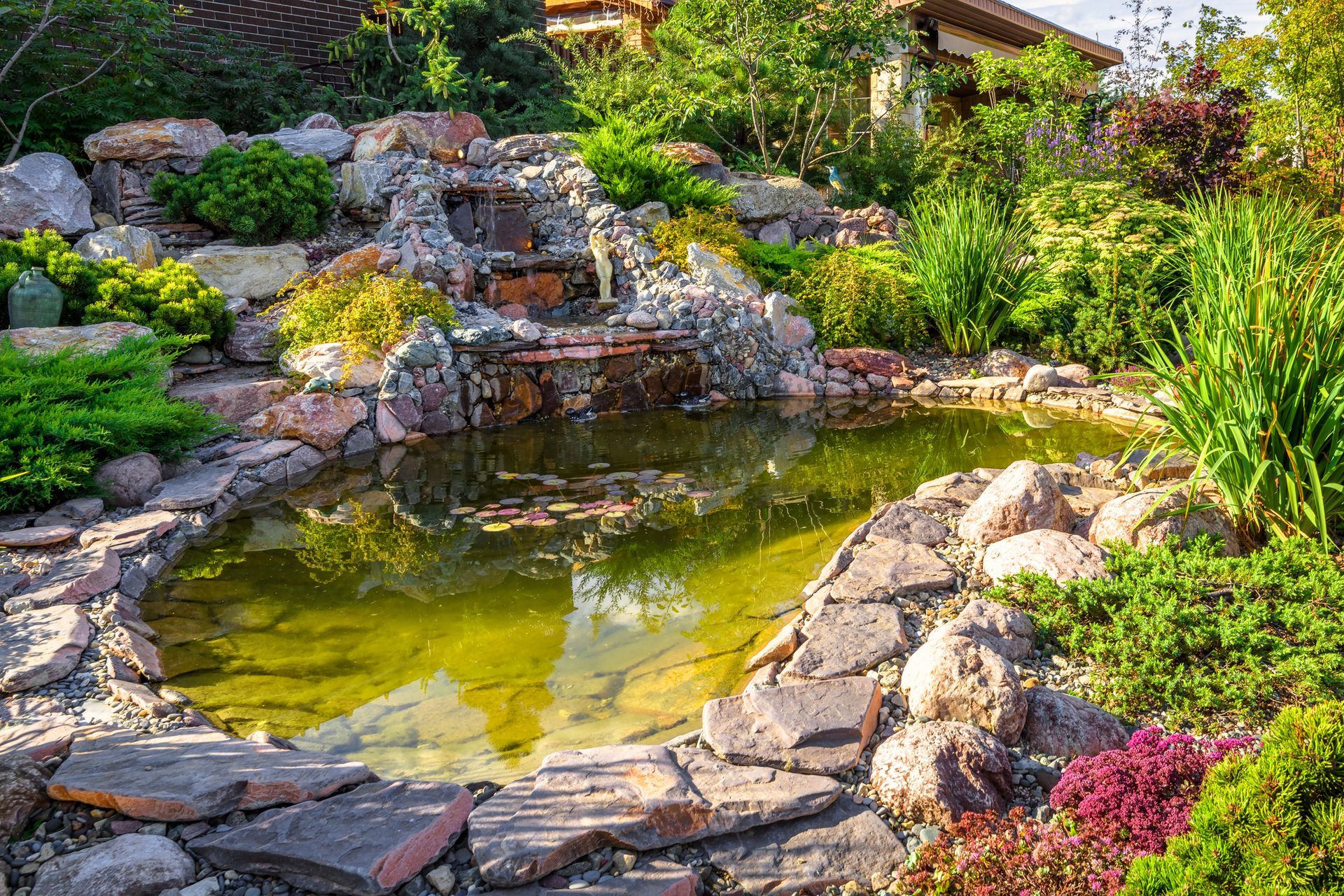 There is a pond in the middle of the garden with a waterfall.