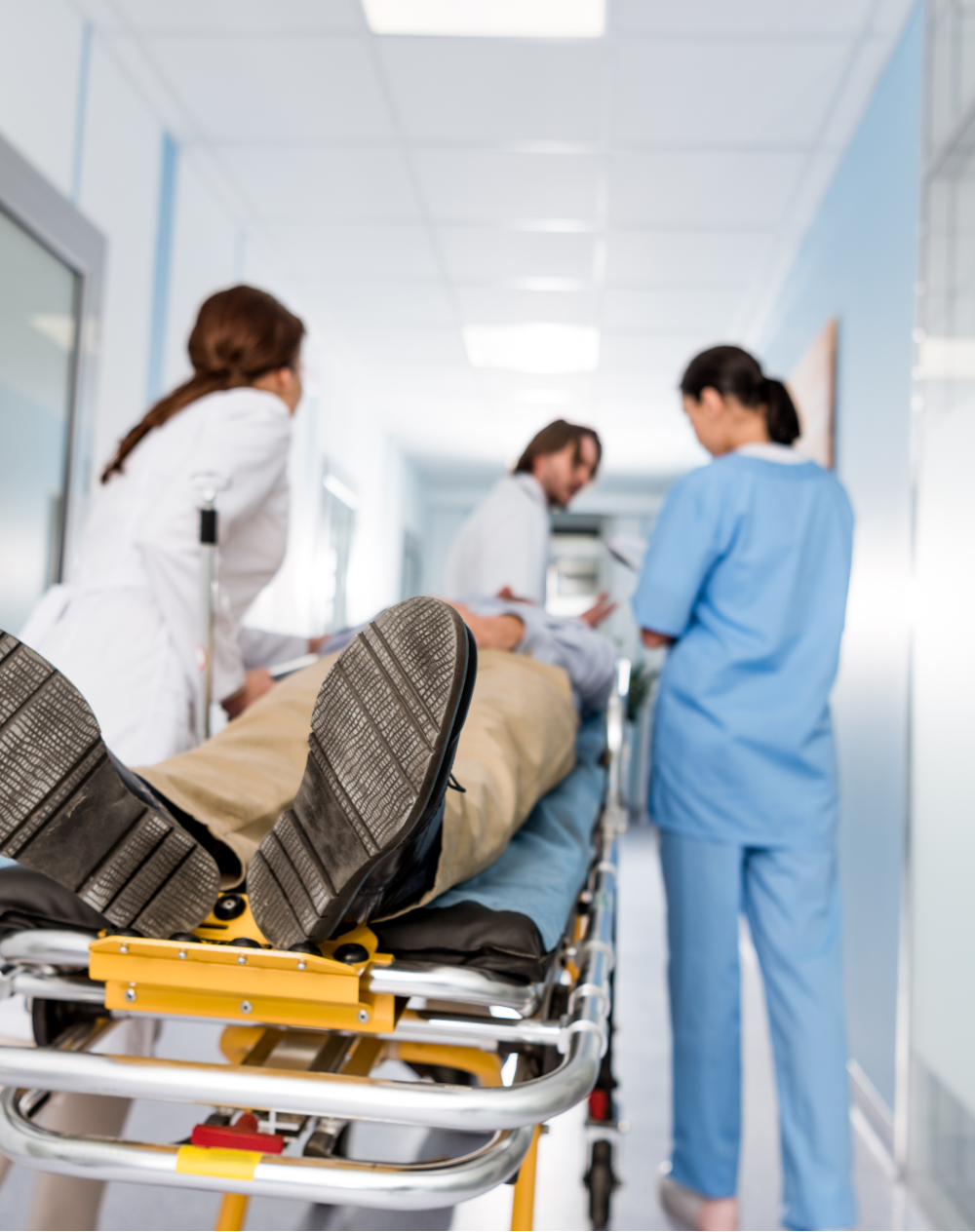 A man is laying on a stretcher in a hospital hallway