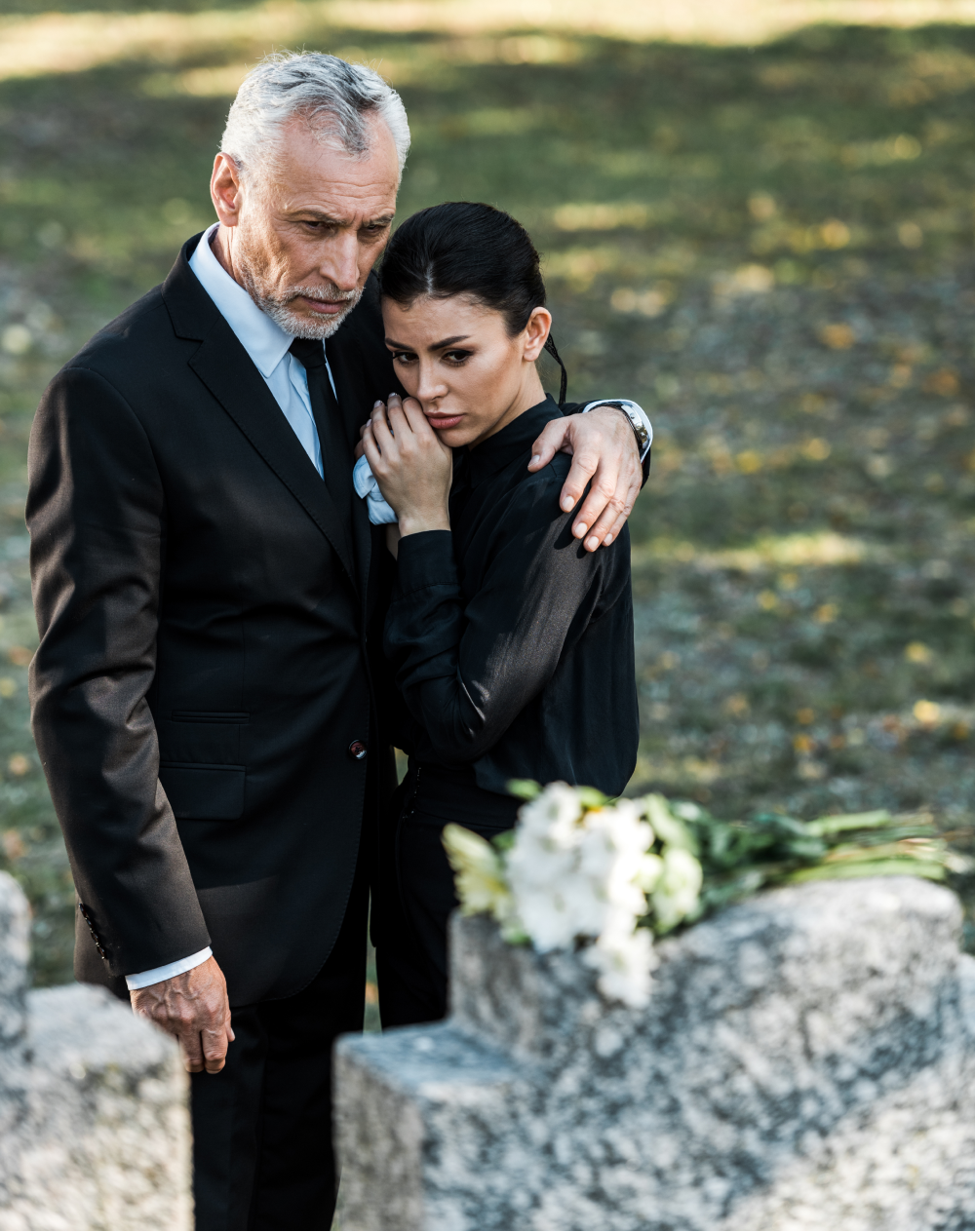 A man and a woman are standing in front of a grave.