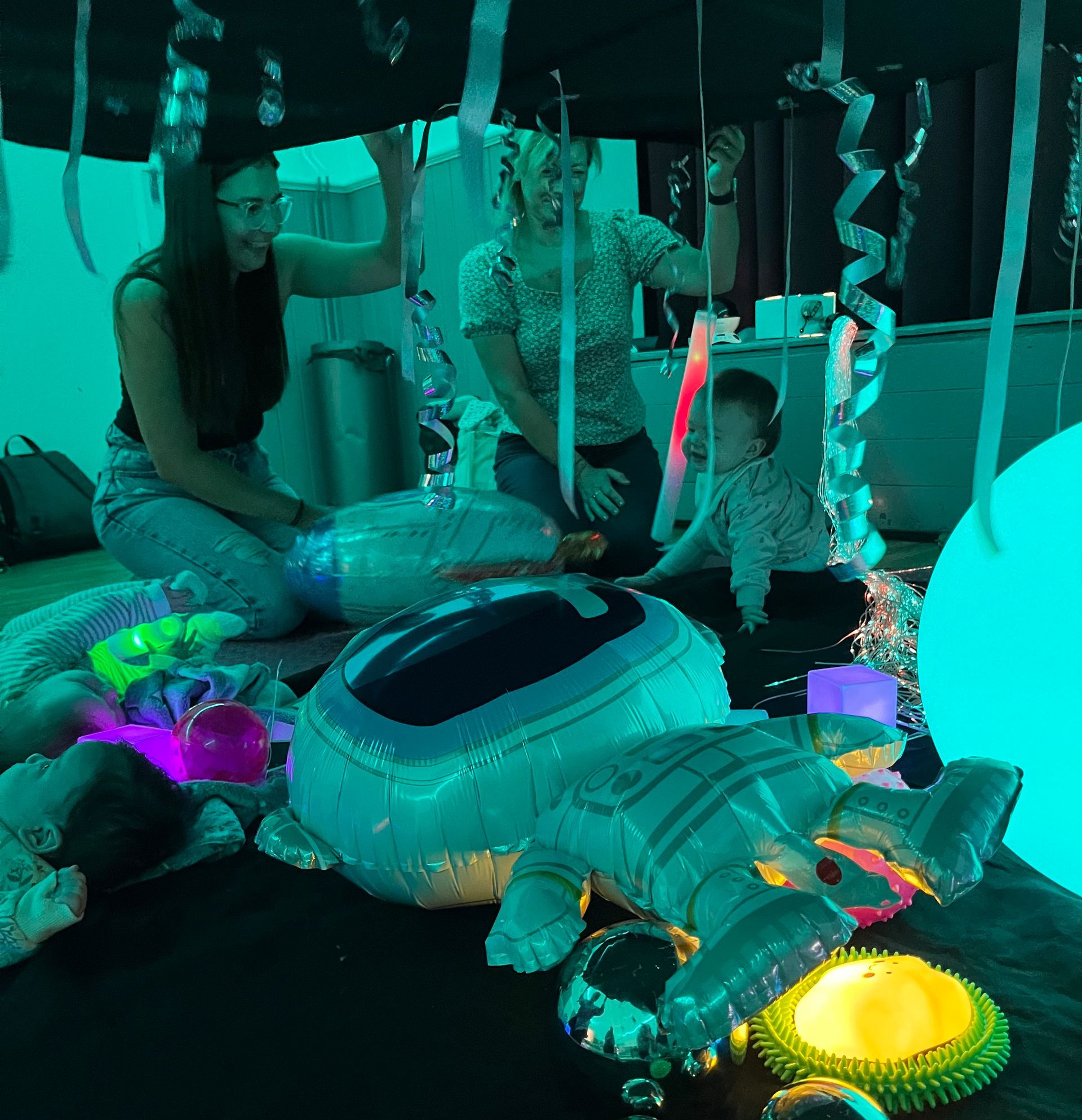 parents and their babies under a space themed parachute