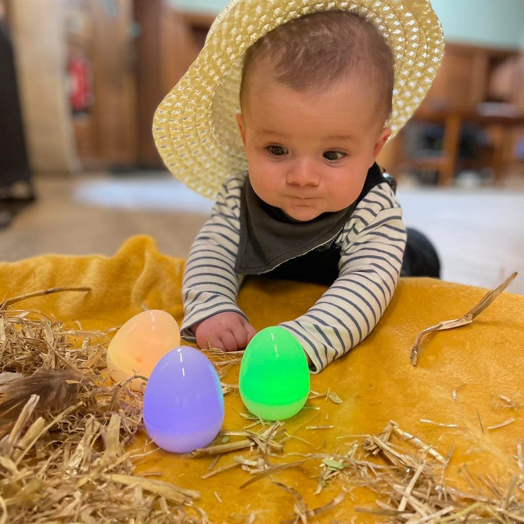a child doing 'tummy time' in a farmers hat
