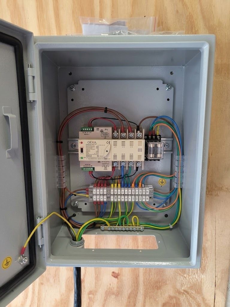Open gray electrical control cabinet with wiring, relays, and circuit components inside.
