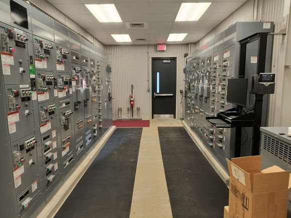 Orange electrical control unit mounted in a white metal cabinet with black cables attached