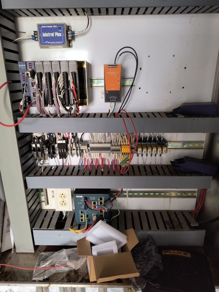 Open electrical control panel with wiring, relays, and circuit modules inside a metal cabinet.