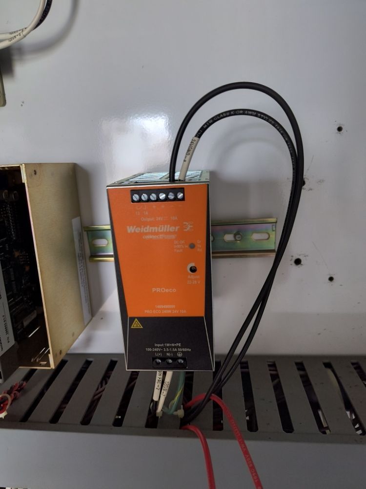 Orange industrial control box with black cables mounted on a metal panel inside an electrical enclosure