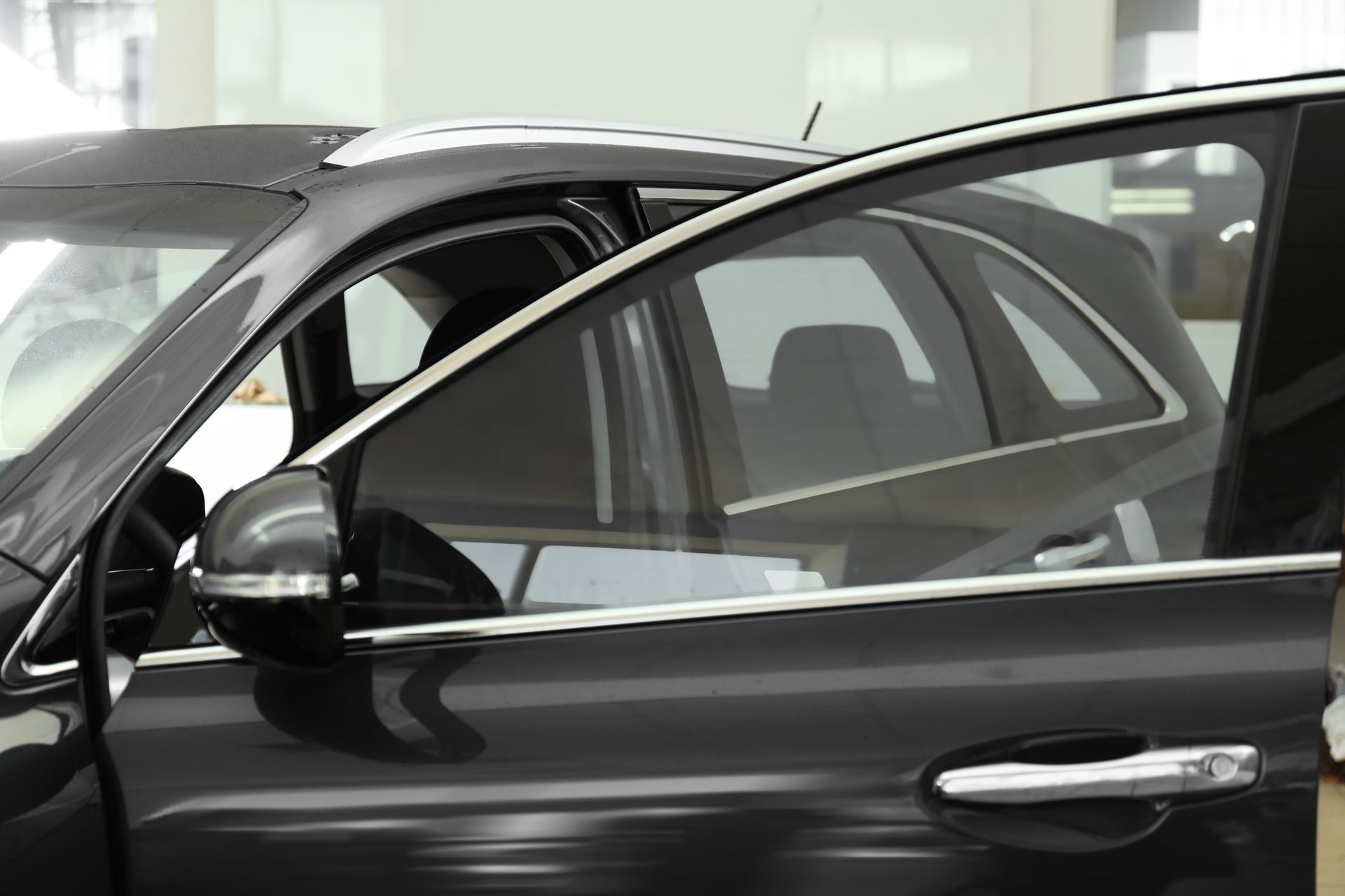 Gray car side mirror next to an open door, reflecting the vehicle interior.
