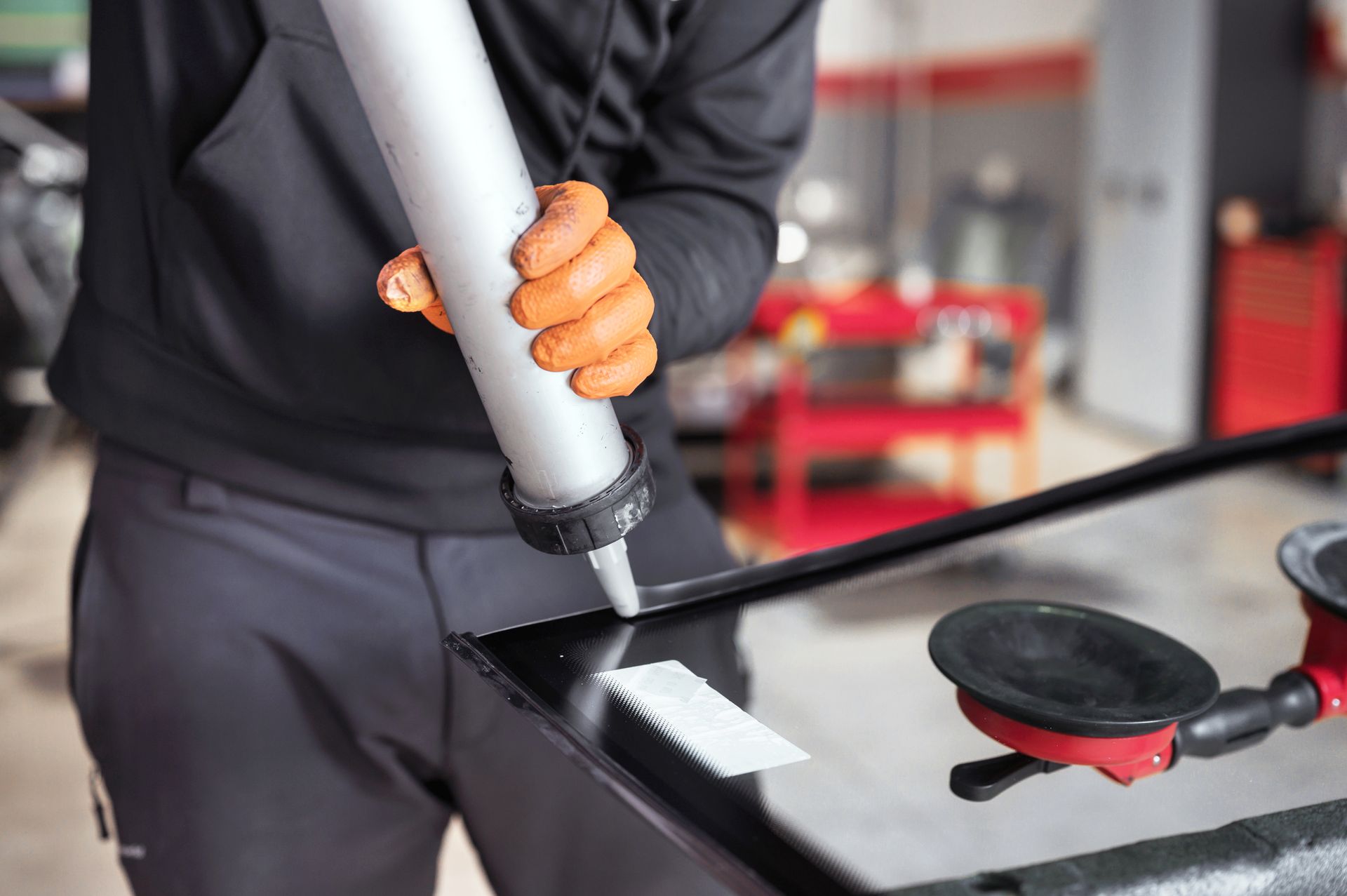 Person applying a windshield chip repair tool to a car window in a garage
