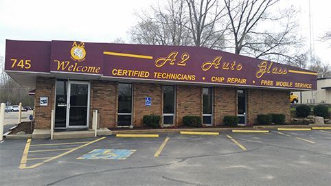 Front view of a brick A2 Auto Group storefront with maroon sign and parking lot in front