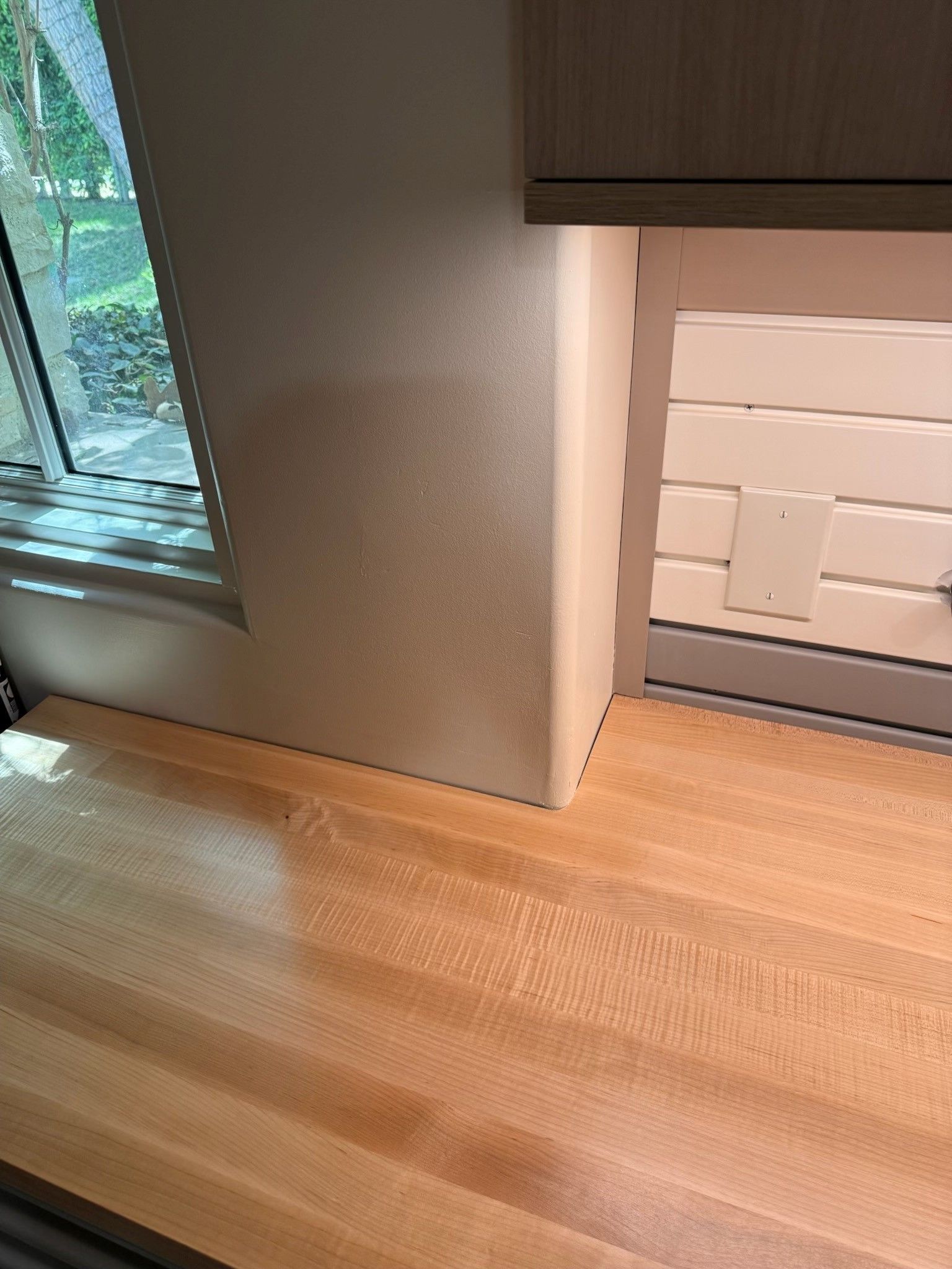 Sunlit wooden floor beside a gray wall and white fireplace in a room