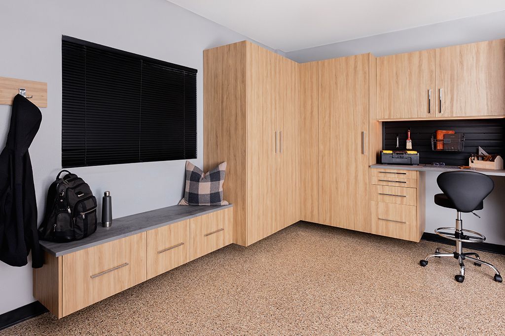 Home office corner with wood cabinets, black window blinds, desk, chair, and coat hooks