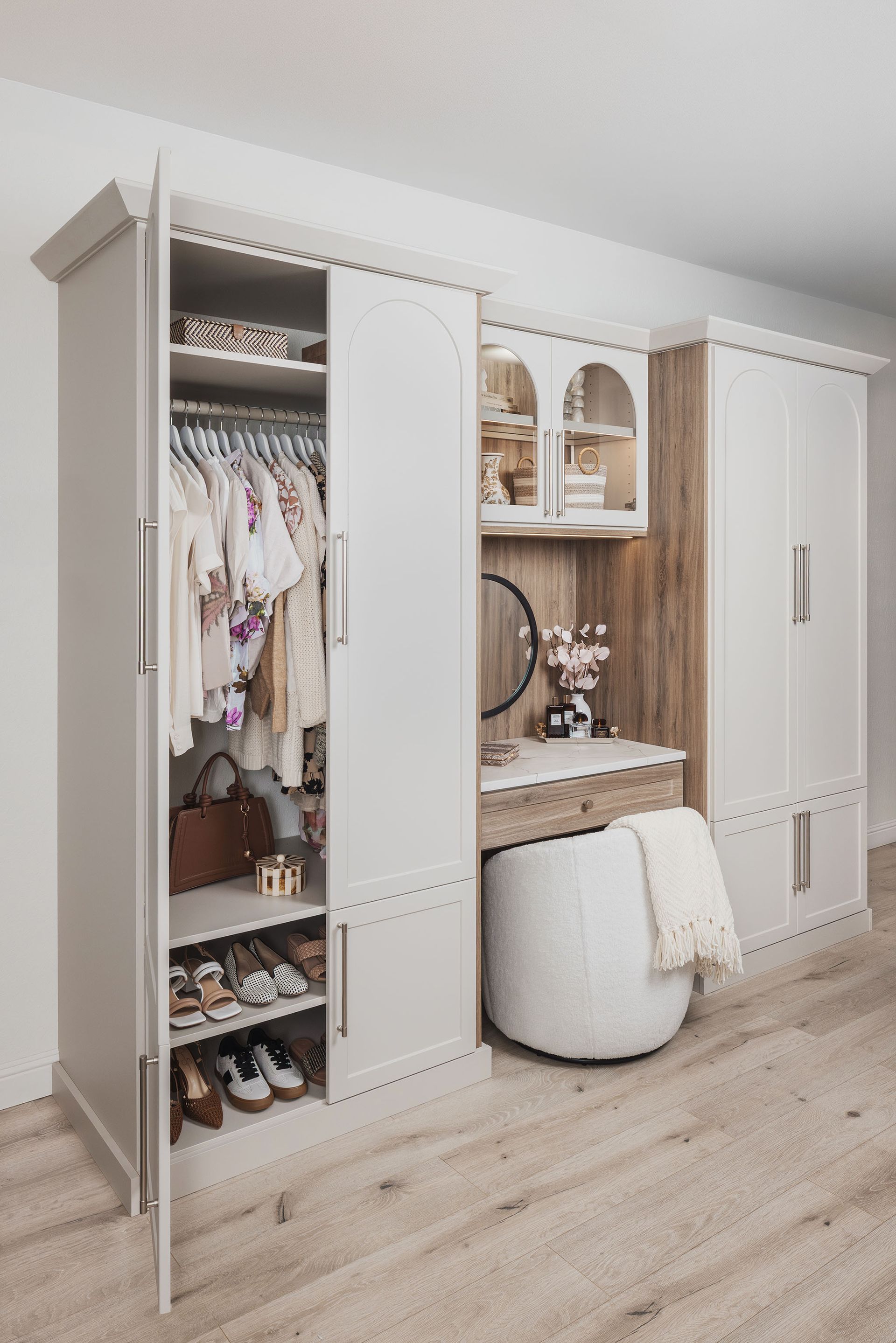 White walk-in closet with open clothing storage, shelves, and a vanity area in a bright bedroom
