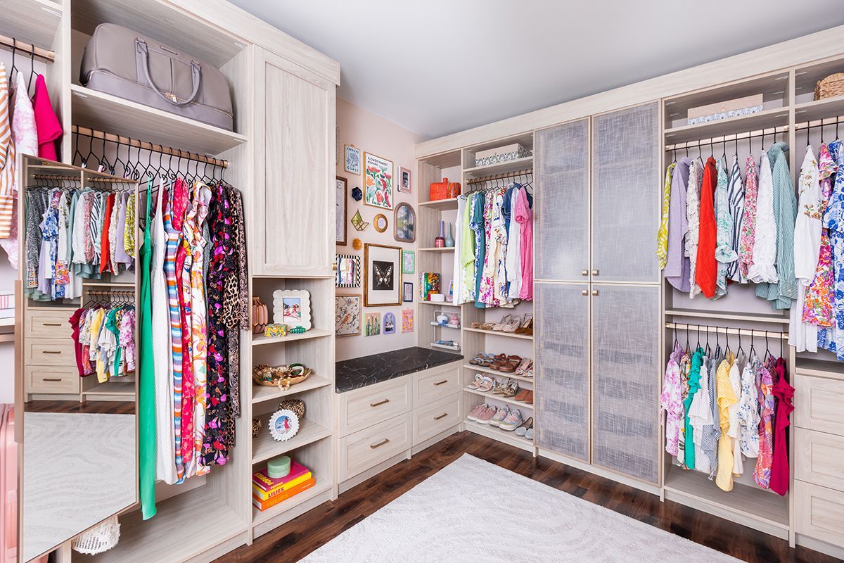 Spacious walk-in closet with colorful hanging clothes, shelves, drawers, and mirrored doors.