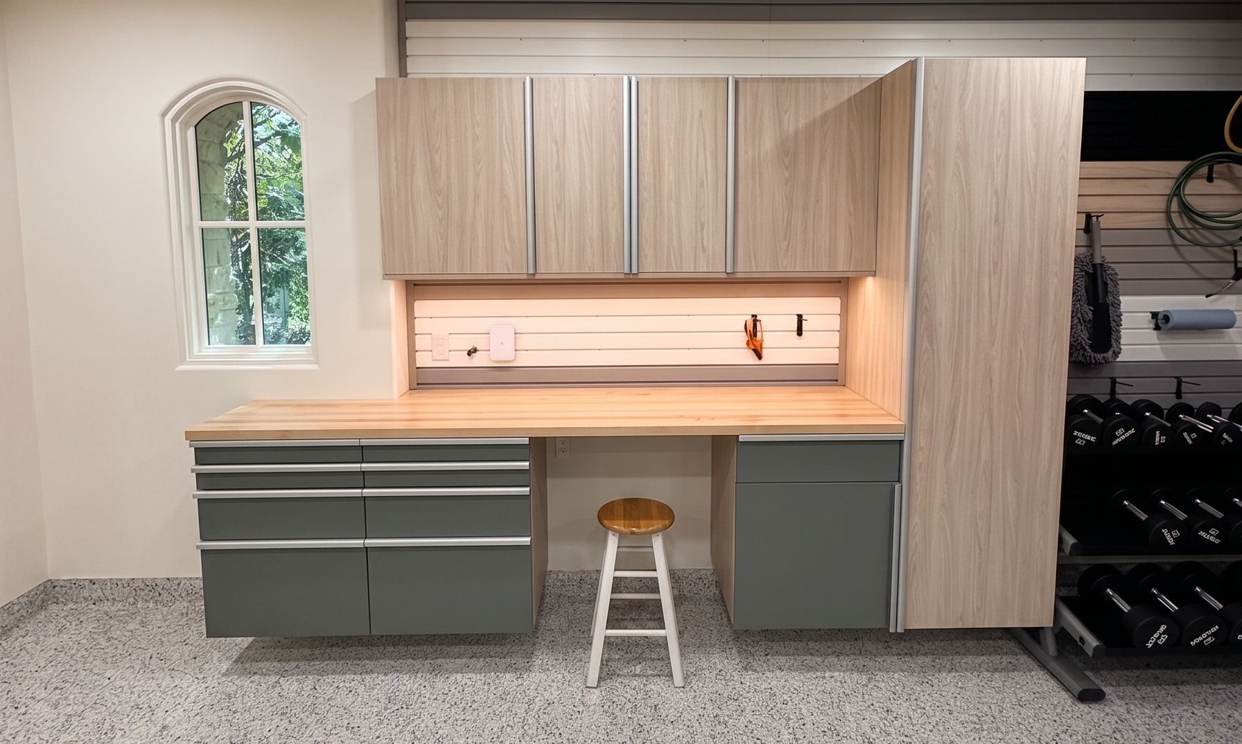Built-in garage cabinetry with wood upper cabinets, gray drawers, and a small stool in front