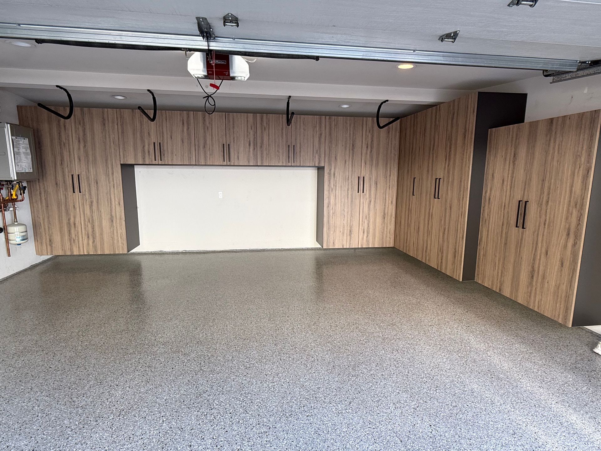 Empty garage with wood-paneled walls, gray speckled floor, and a white garage door.