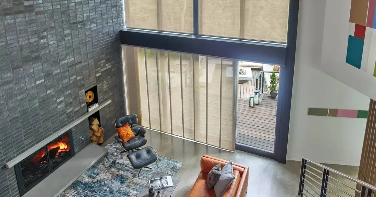 An aerial view of vertical shades, a living room with a fireplace and a couch.