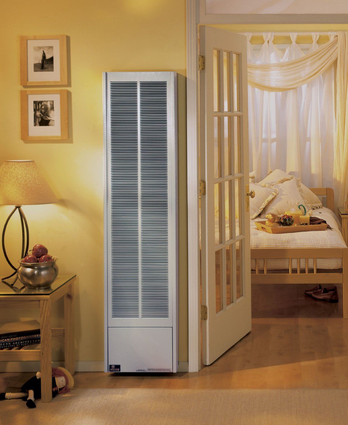 Tall white air conditioner in a cozy yellow room beside an open doorway to a bed with white curtains