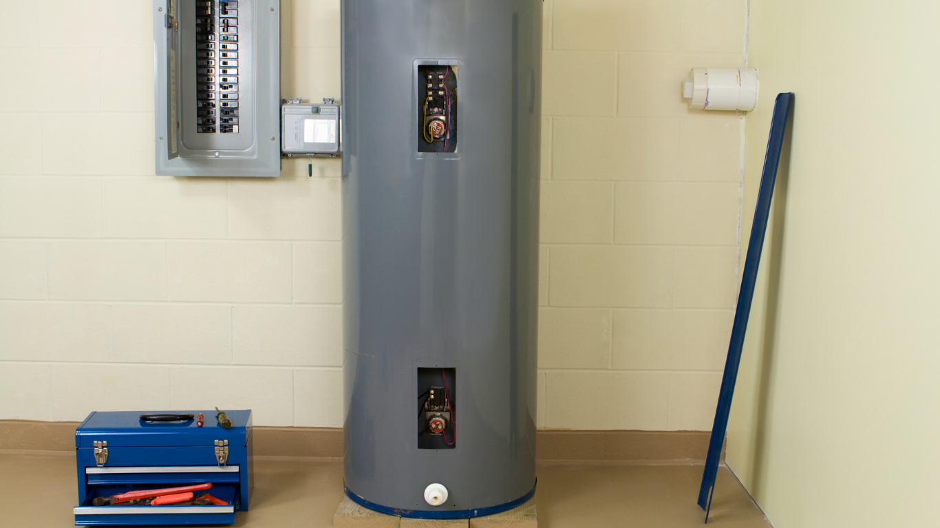Utility room with a gray water heater, blue toolbox, wall panel, and broom leaning against the wall.