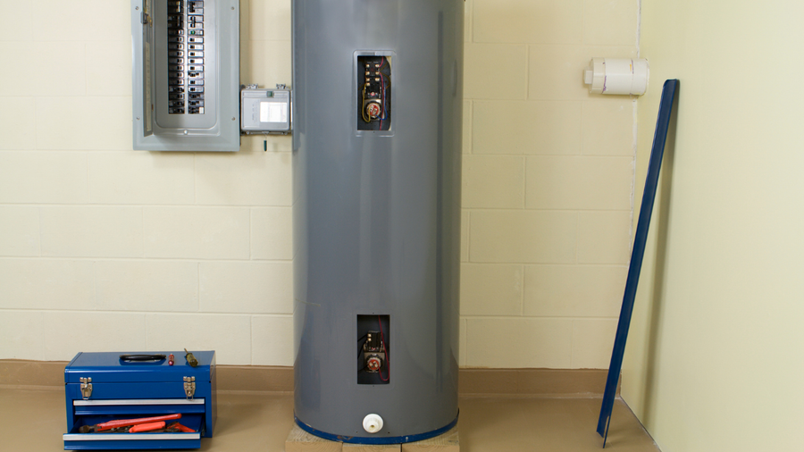 Utility room with a gray water heater, blue toolbox, wall panel, and broom leaning against the wall.