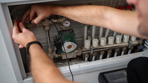 Technician adjusting plumbing or irrigation valves inside a utility cabinet