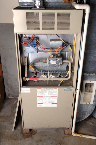 Open furnace with exposed wiring and components in a utility room