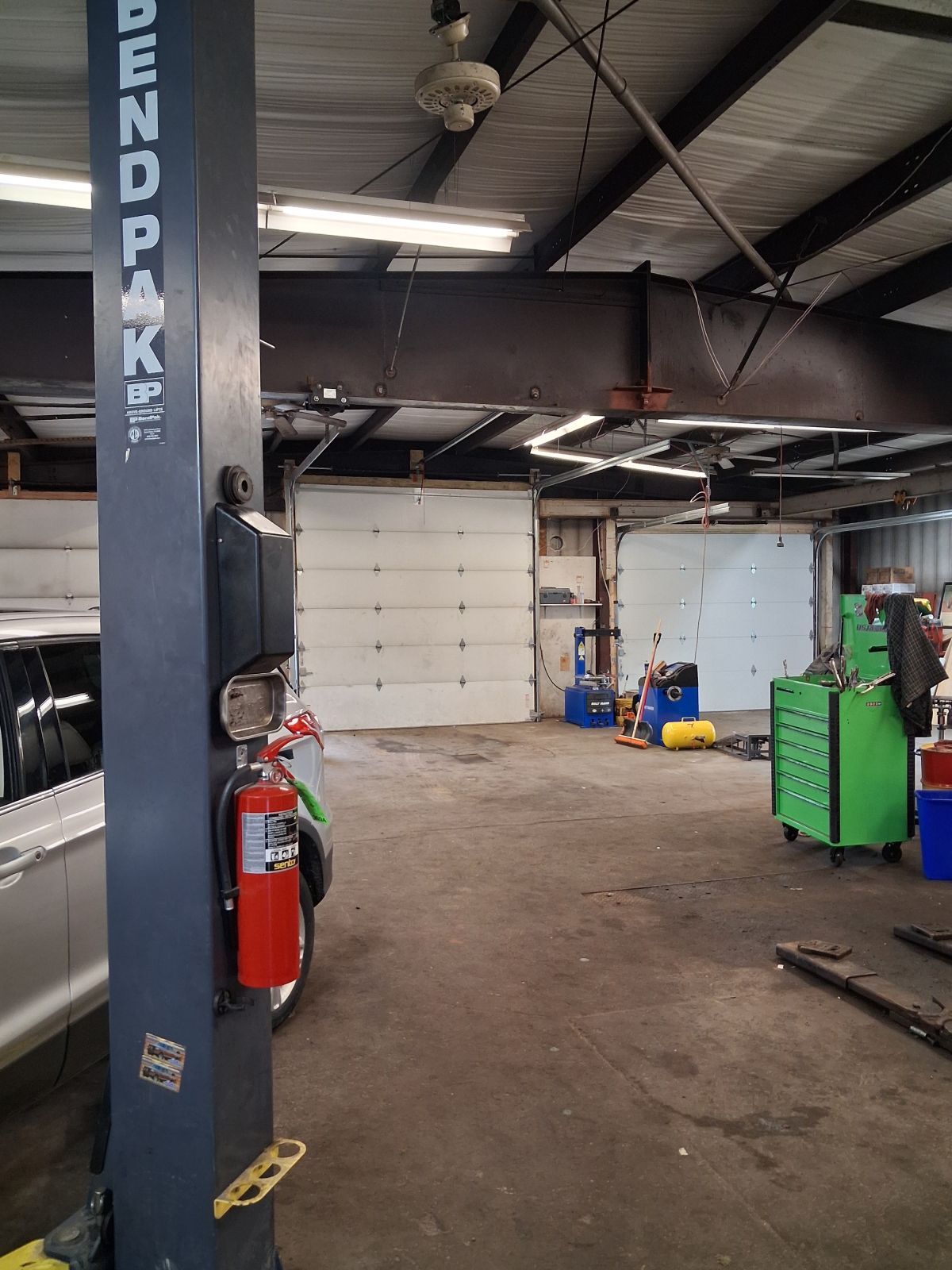 Auto repair garage with a vehicle lift, fire extinguisher, and garage door. | Kensinger Repair Center