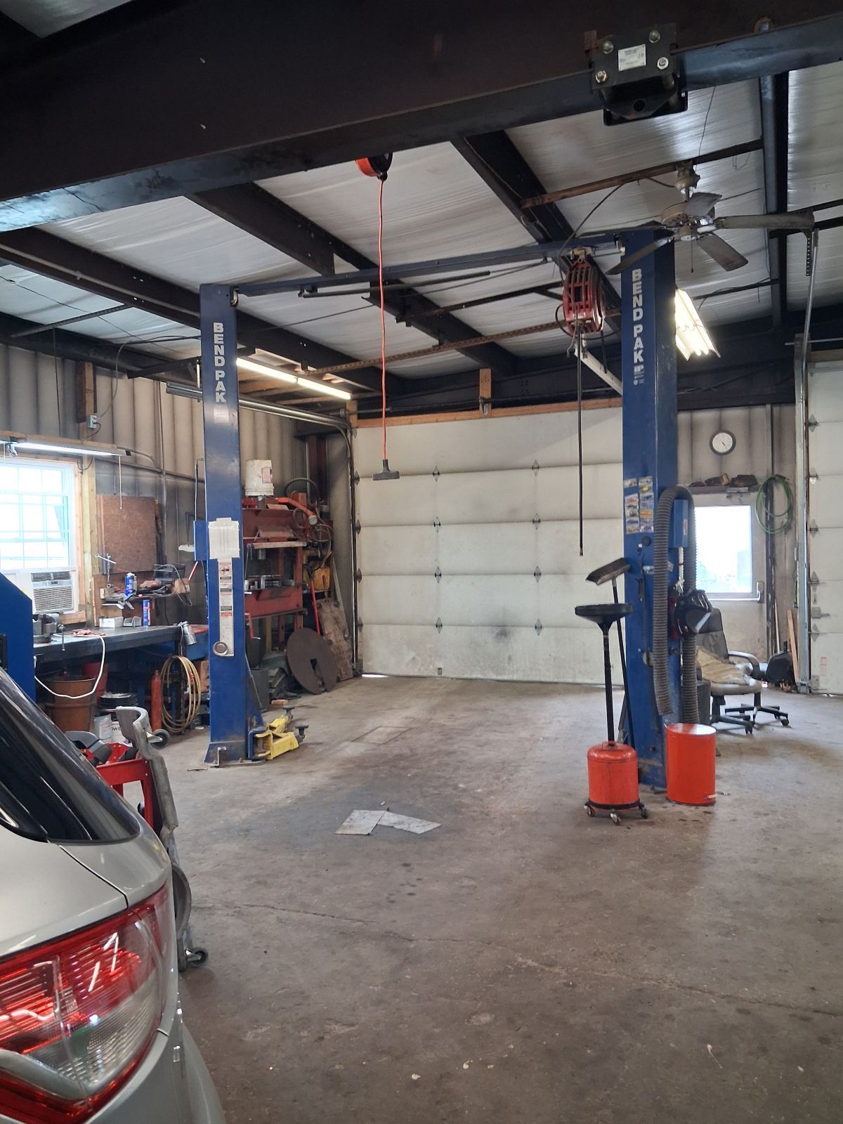 Auto repair shop with car lift, parked car, and large garage door | Kensinger Repair Center