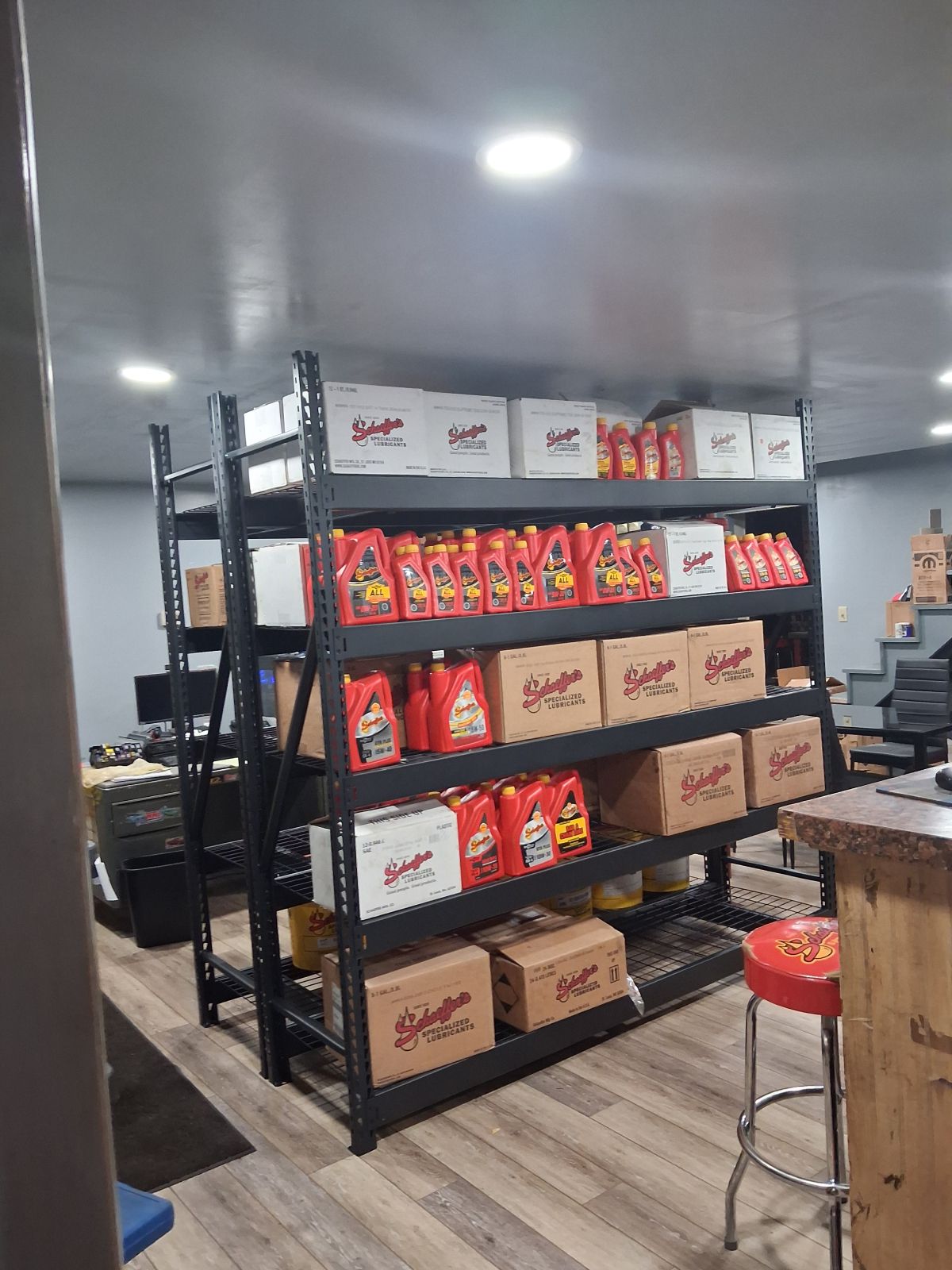 Retail storage room with black shelves stocked with boxed snacks and supplies under bright ceiling lights | Kensinger Repair Center