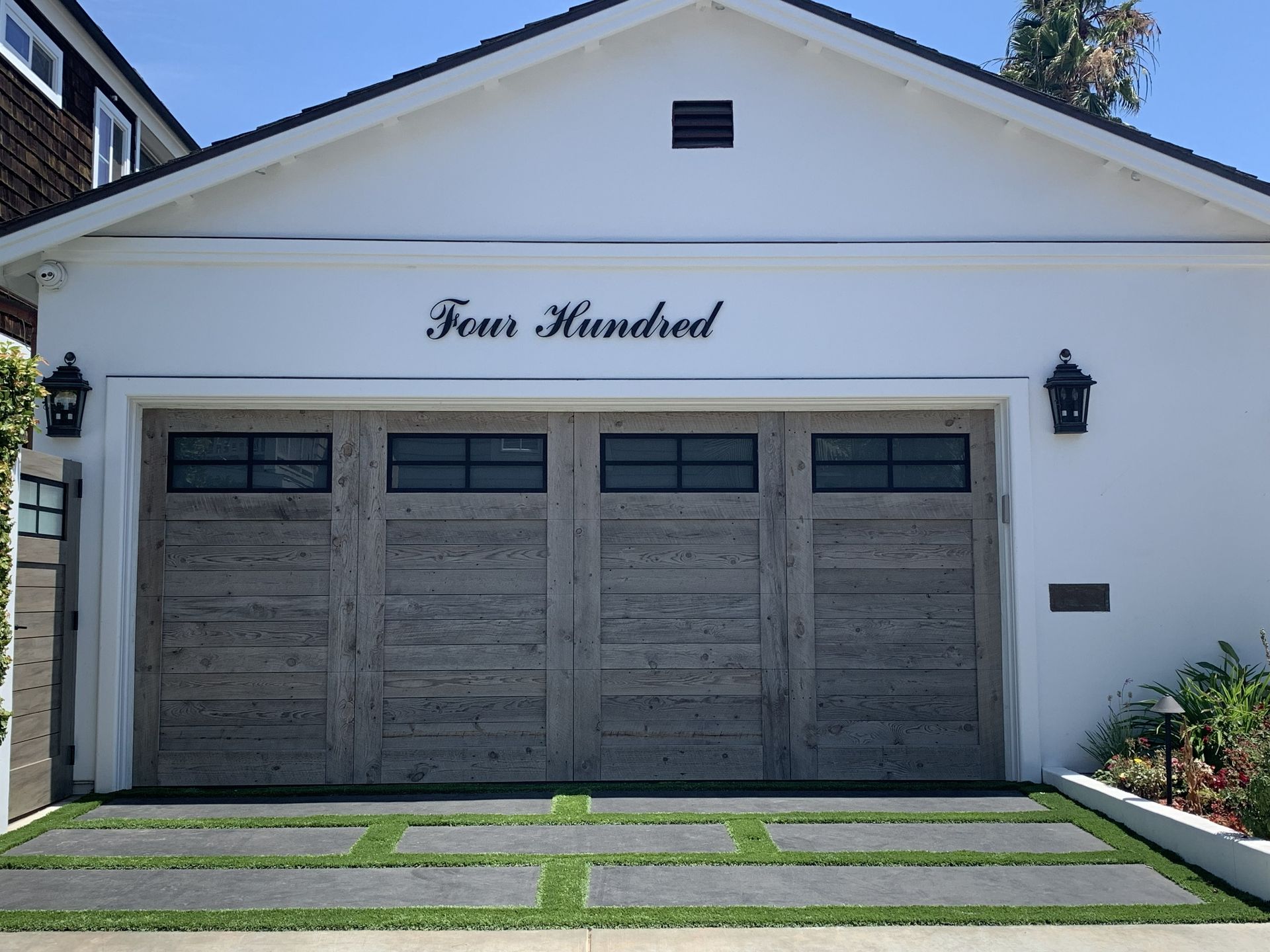 White house garage with three gray doors and the name “Sam Mitchell” above them