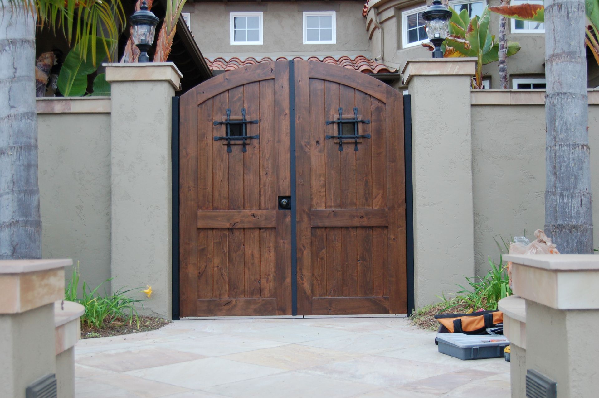 Wooden double front gate between stucco pillars at a house entrance