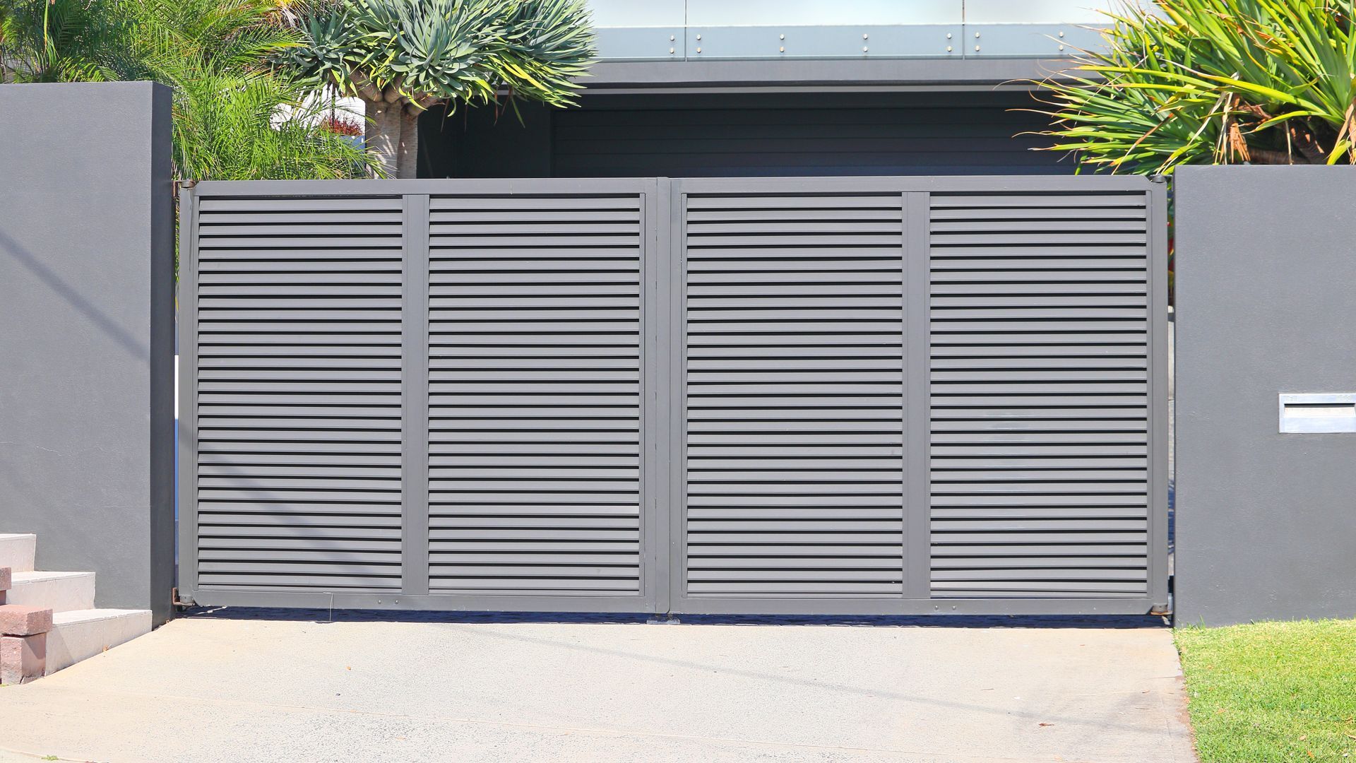 Gray front gate with horizontal slats at a modern house entrance