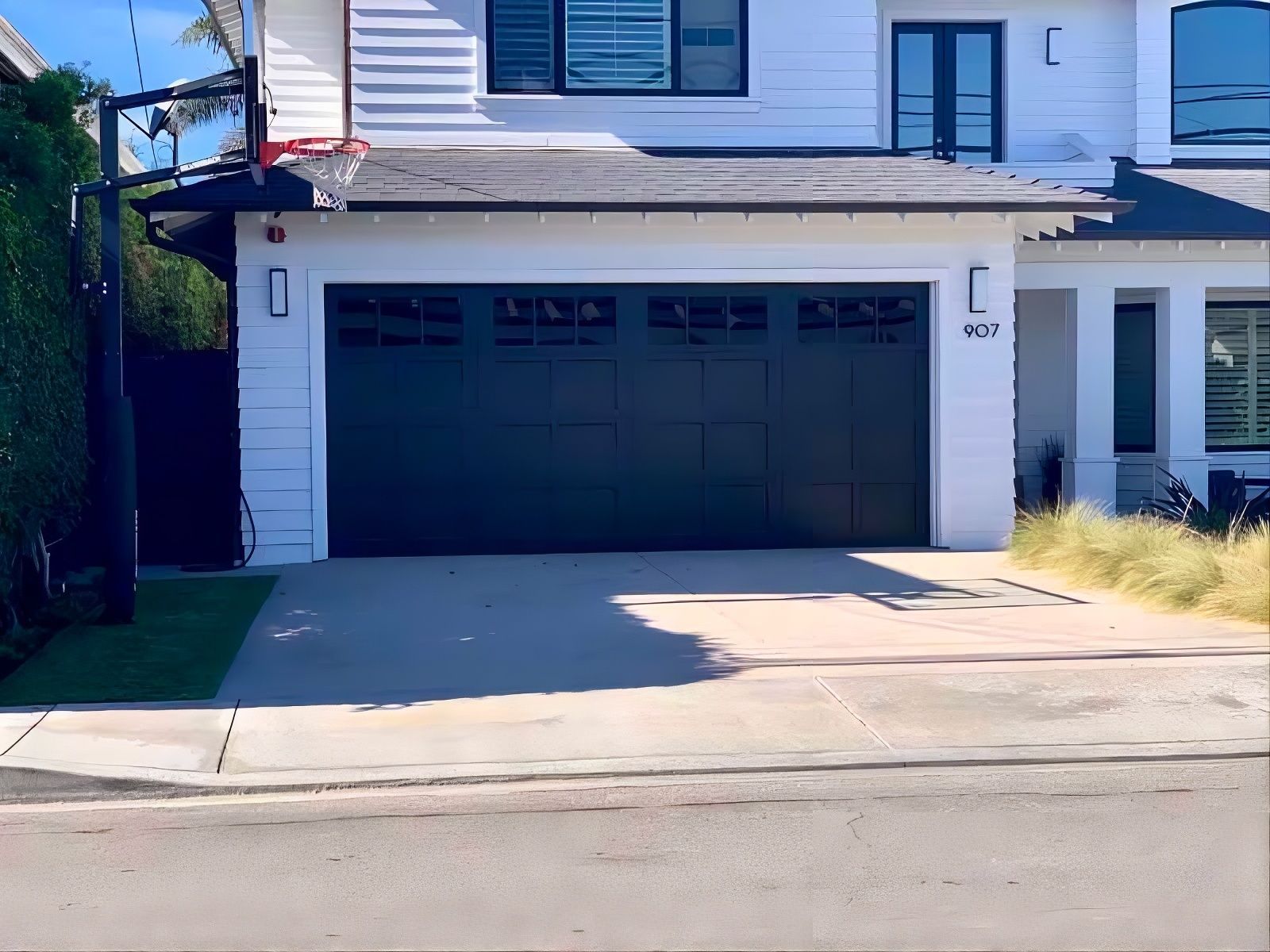 Modern two-story house with a dark garage door and driveway in front