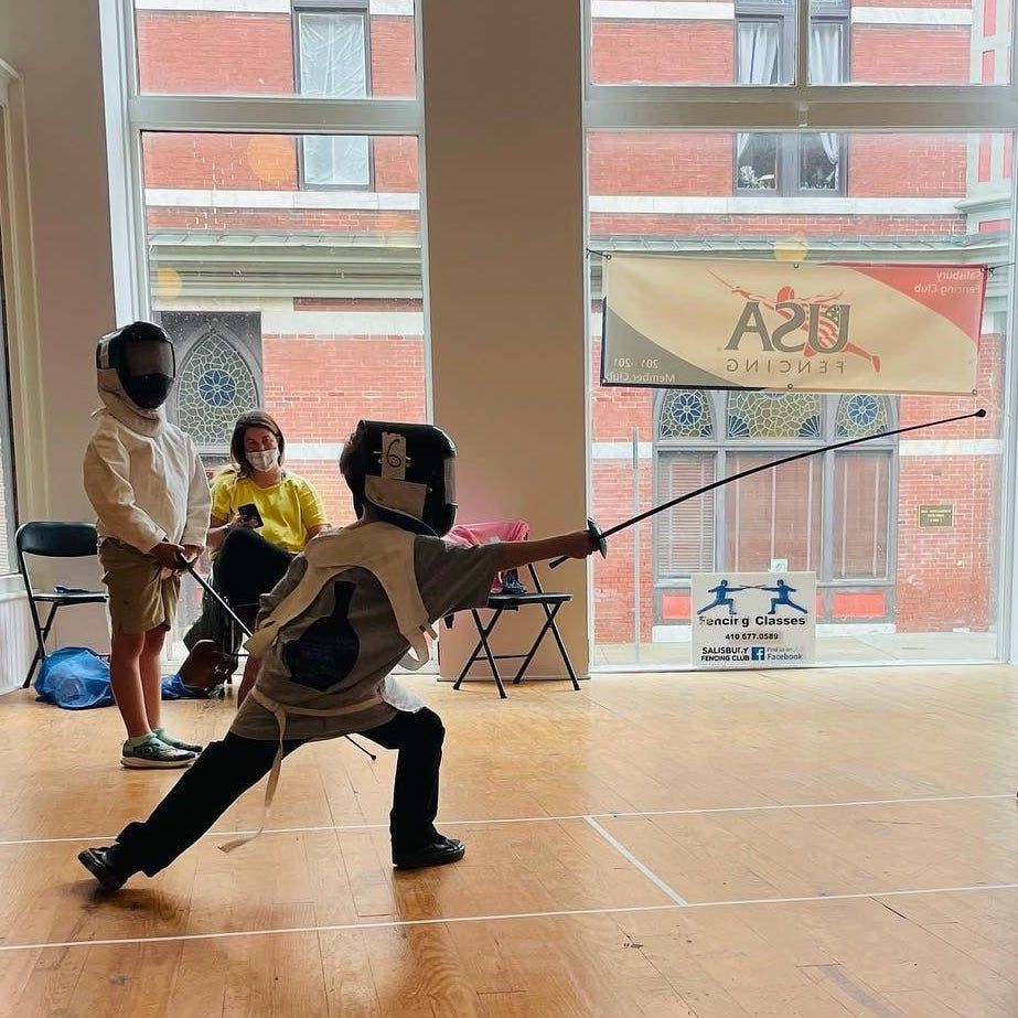 A young fencer lunges at practice as others watch