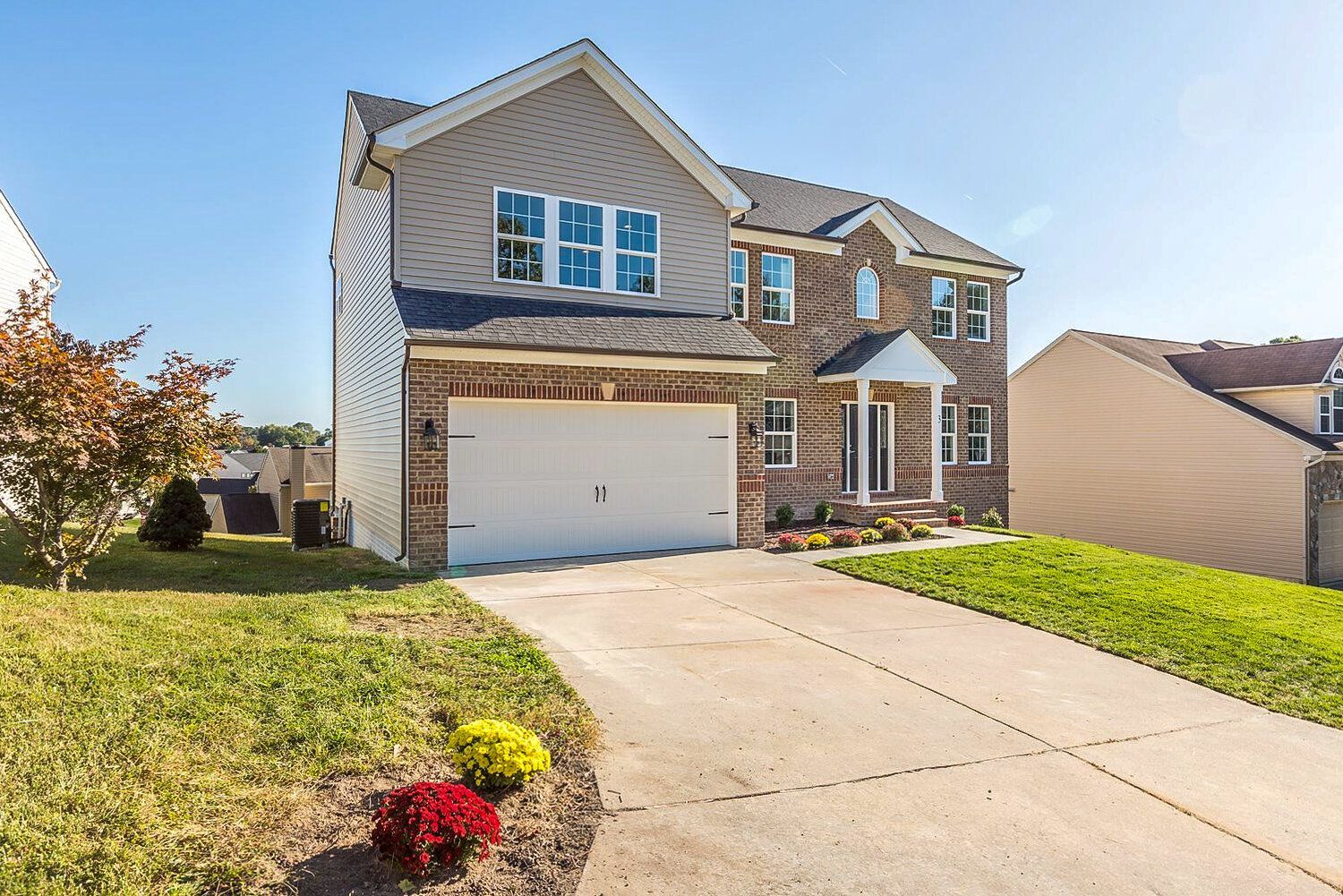 A large house with a white garage door is sitting on top of a lush green hillside.
