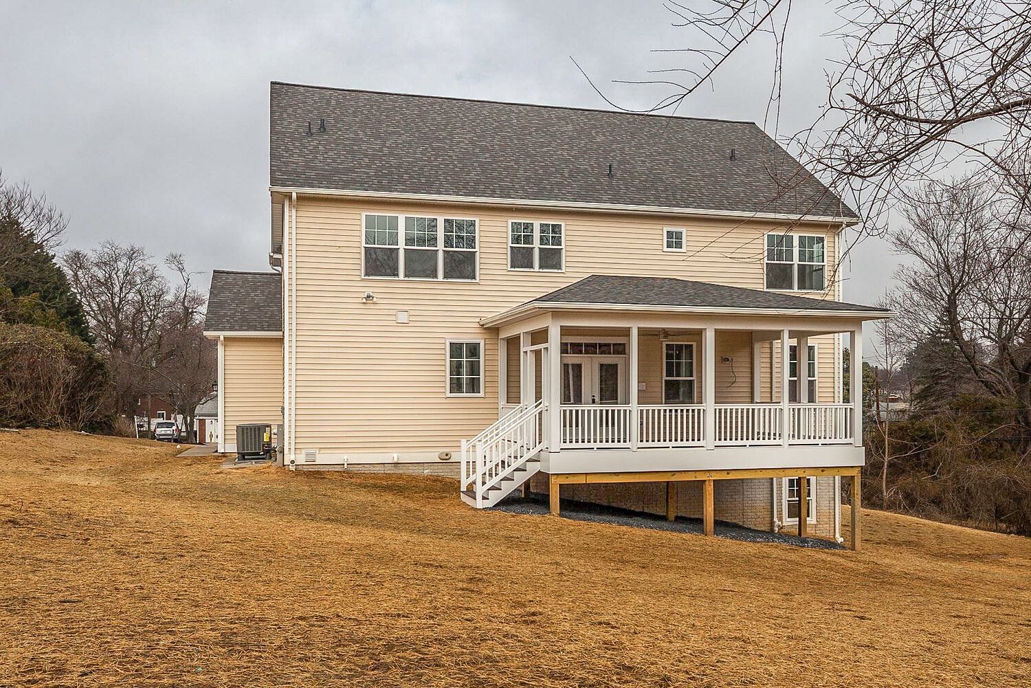 The back of a house with a large porch and stairs.