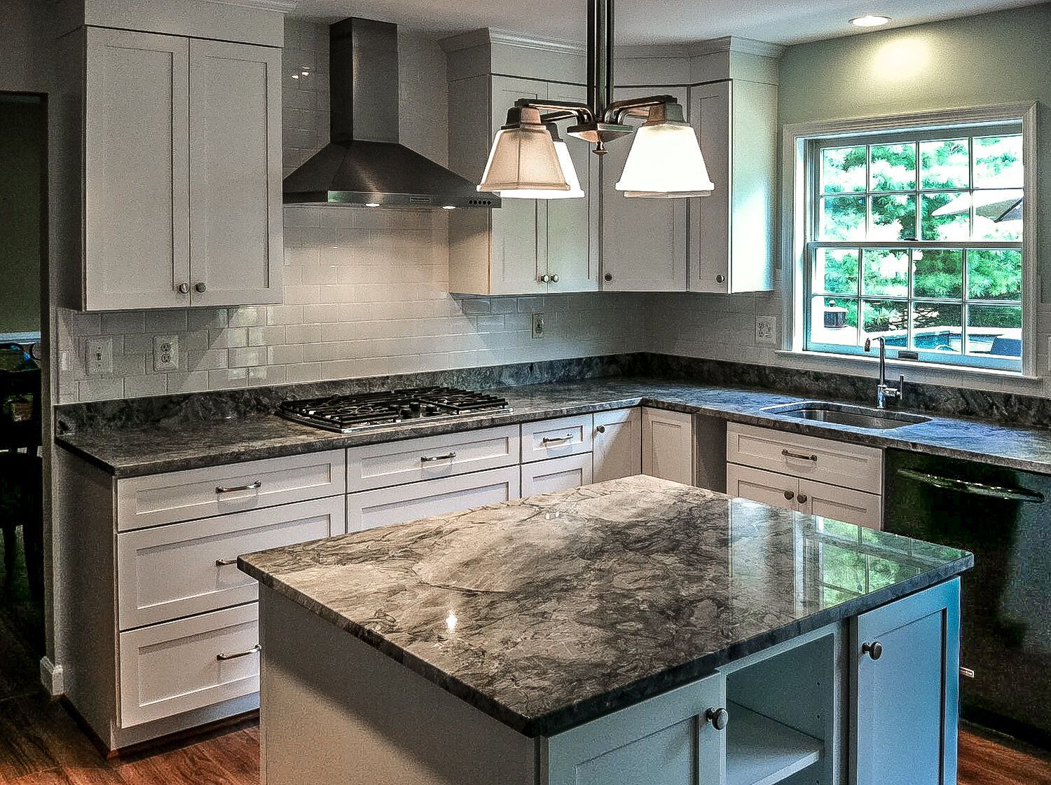 A kitchen with granite counter tops and white cabinets
