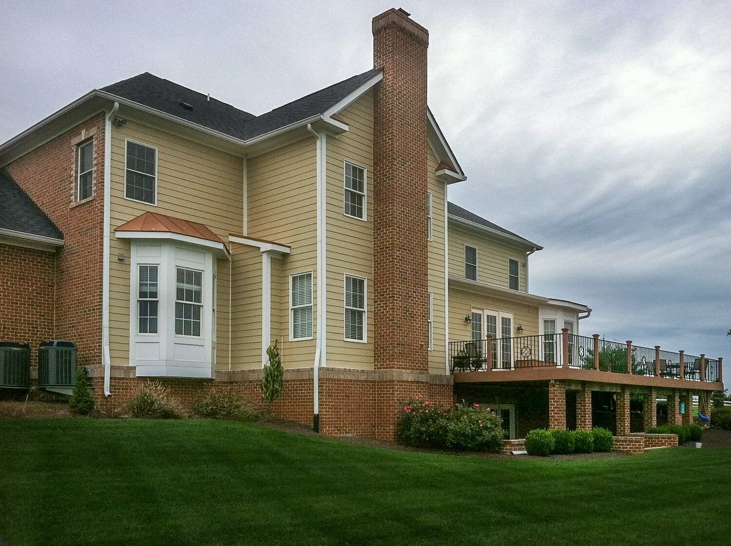 A large house with a brick chimney and a large deck