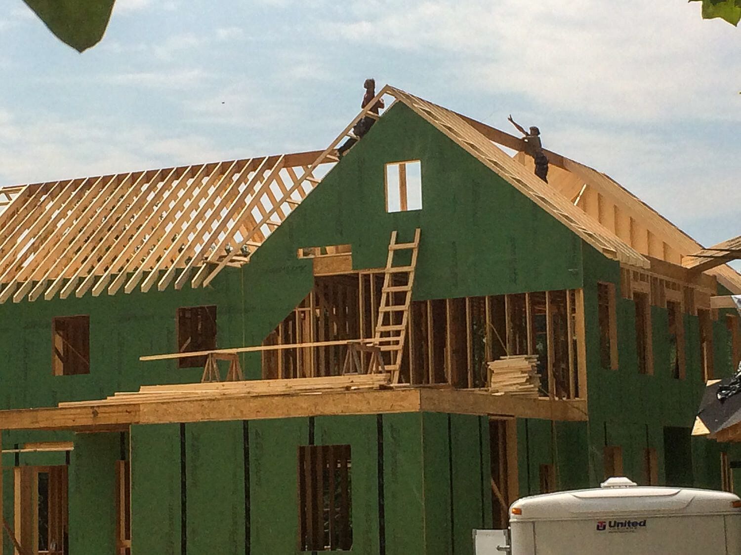 A house that is being built with a ladder on the roof