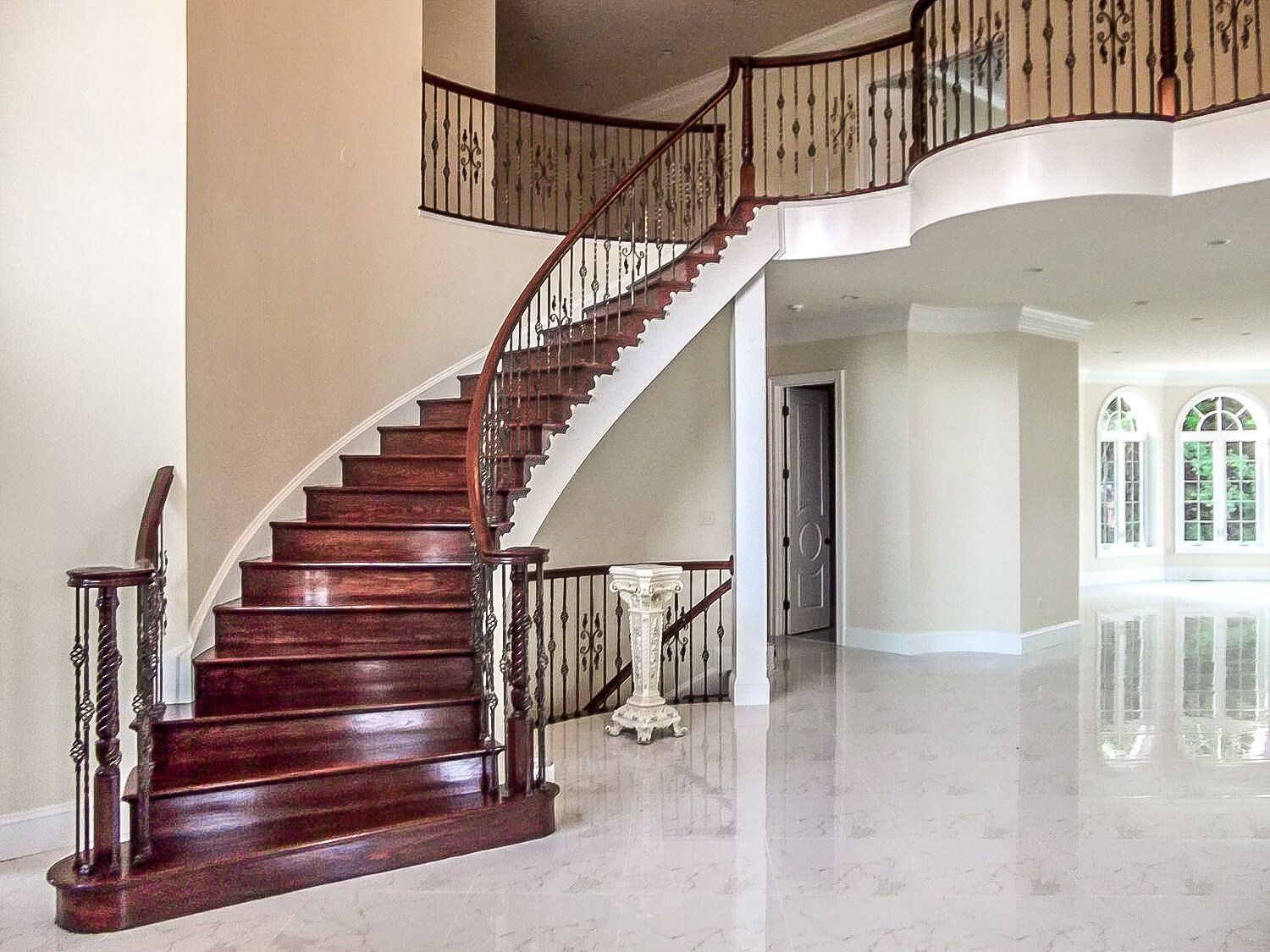 A curved staircase in an empty house with a wrought iron railing.