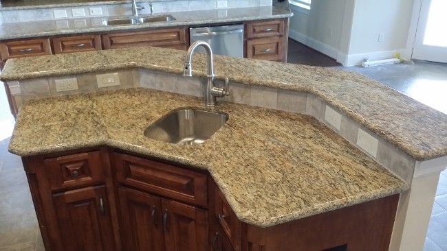 Granite kitchen island with sink and curved breakfast bar in a bright modern kitchen