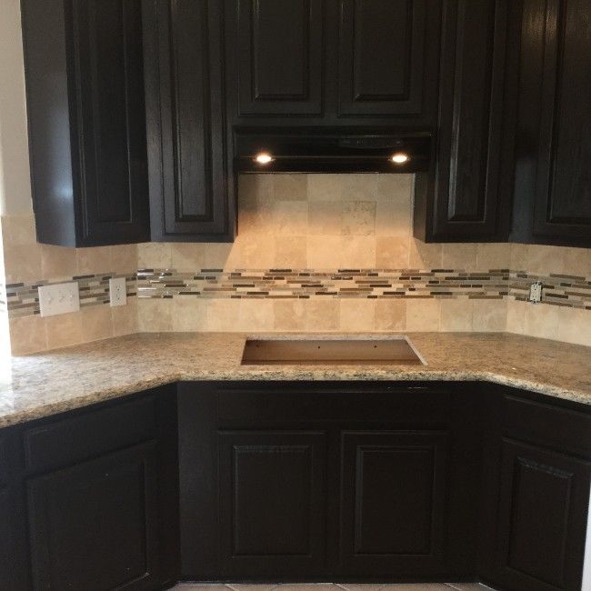 Black kitchen with granite counters, beige tile backsplash, and under-cabinet lights over the sink area