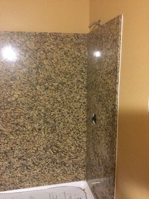 Marble shower stall with glass door and beige walls, viewed from the bathroom corner