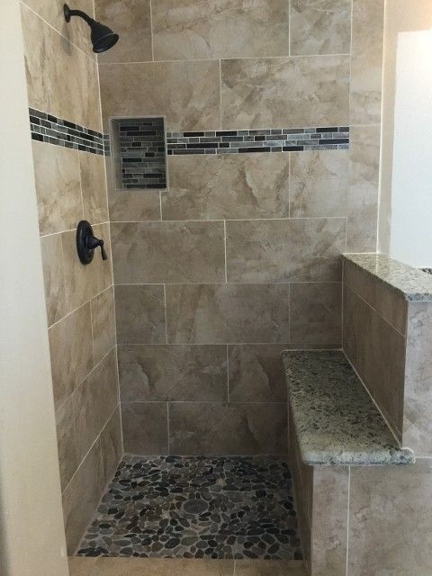 Tiled walk-in shower with pebble floor, wall niche, and granite bench seat.