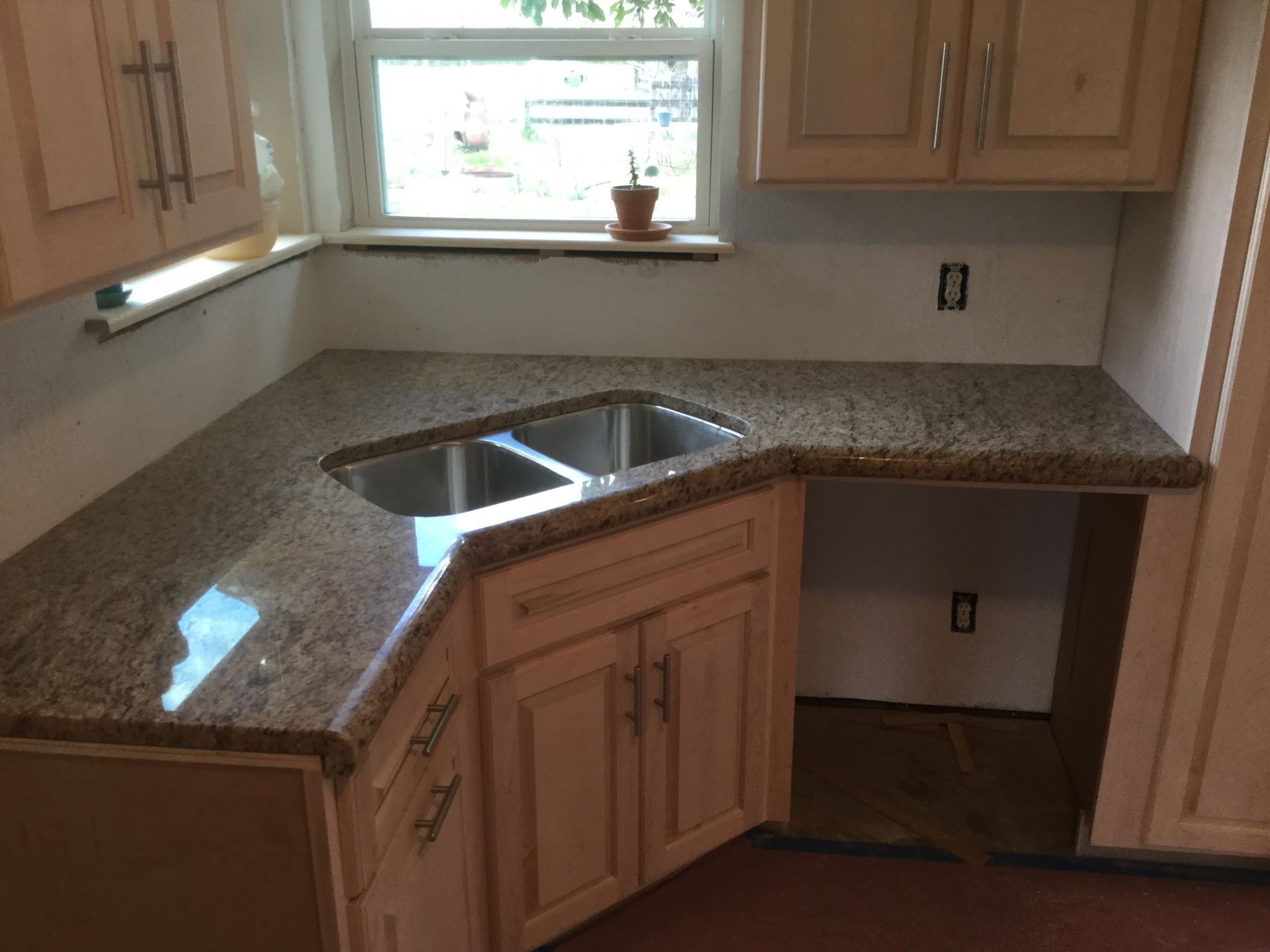 Kitchen with granite countertops, sink under a window, and wooden cabinets, partially unfinished floor area