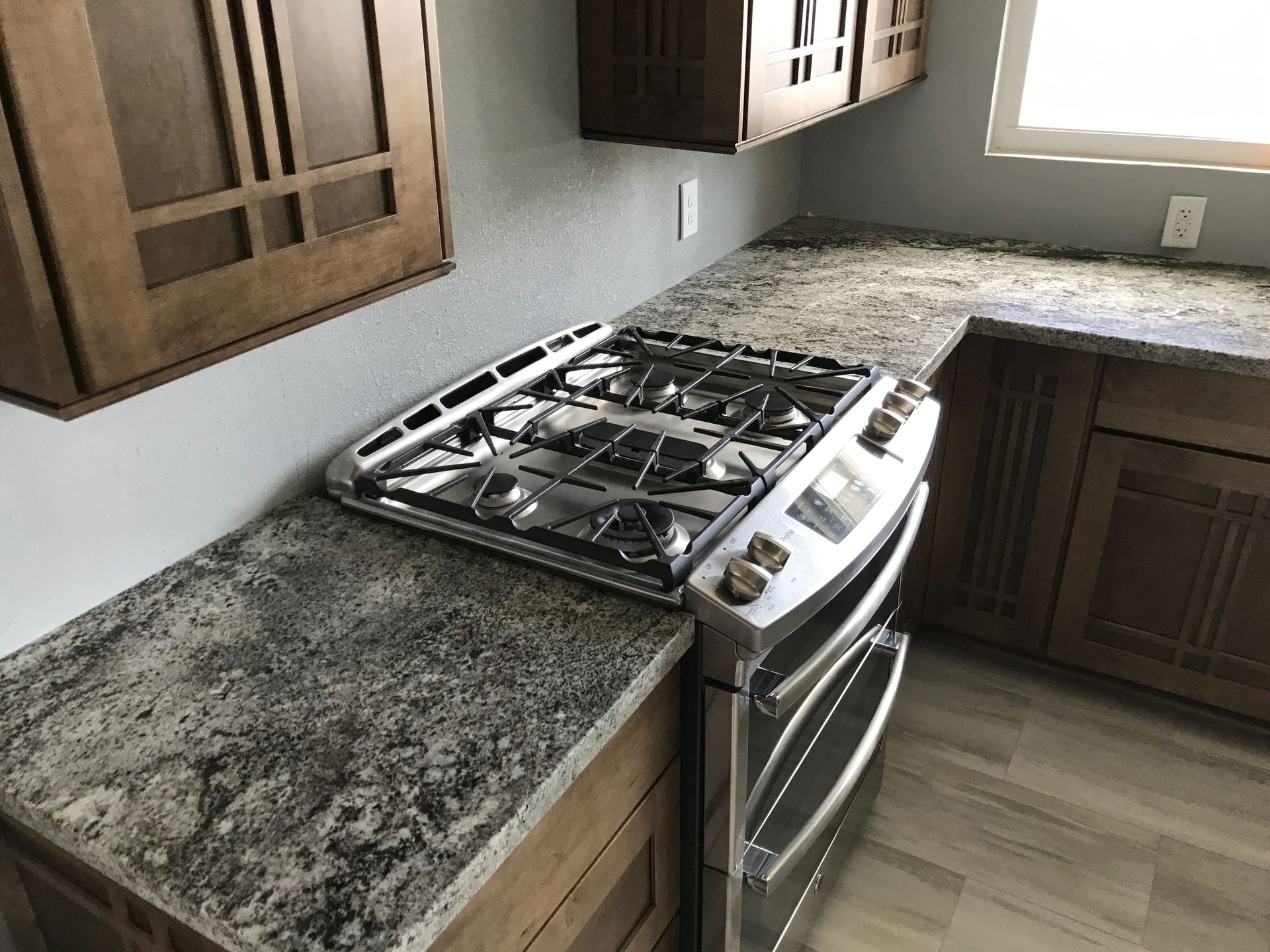 Kitchen with granite countertops, wooden cabinets, and a stainless steel gas stove.